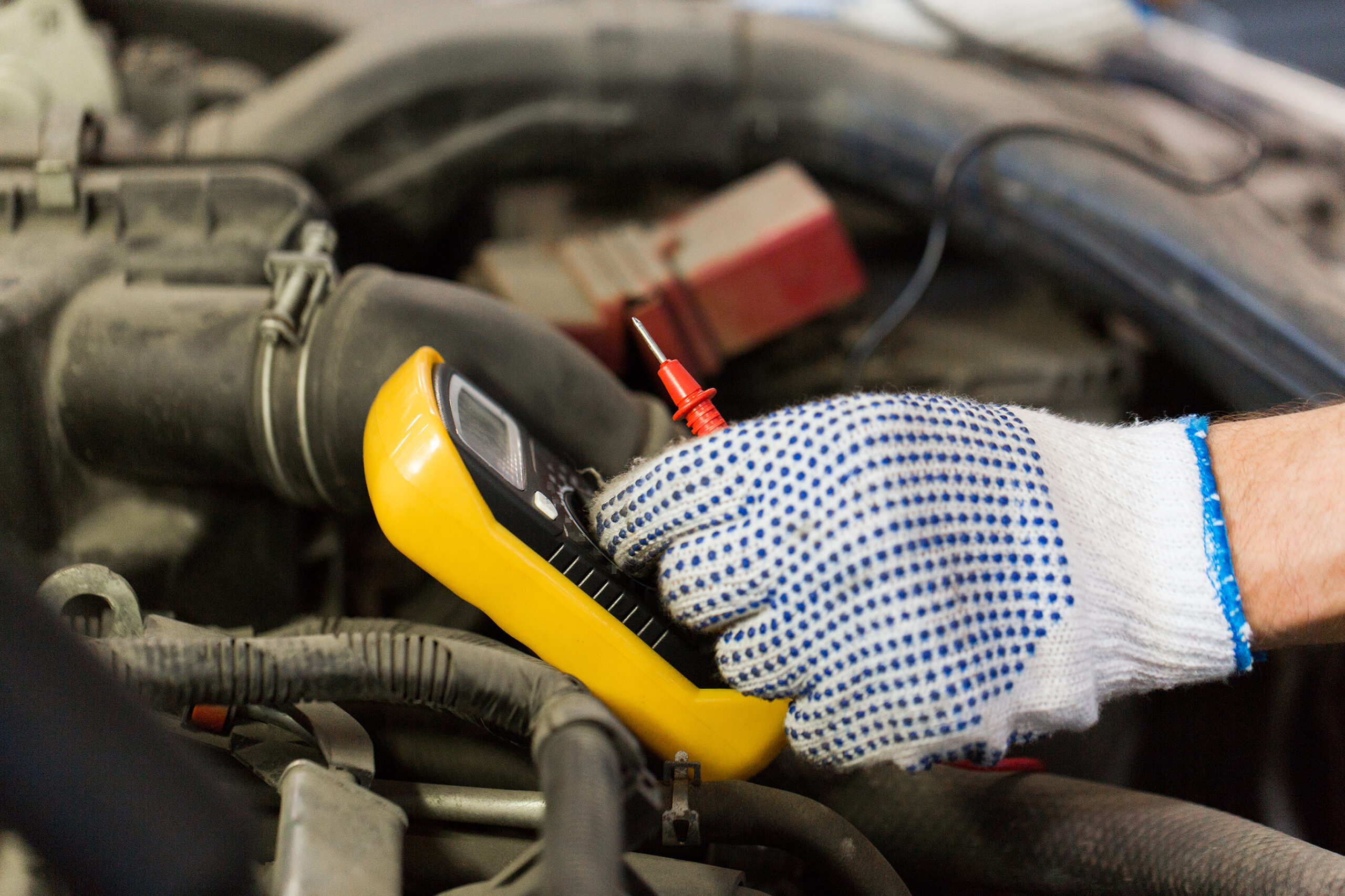 Mechanic testing car battery with multimeter tool