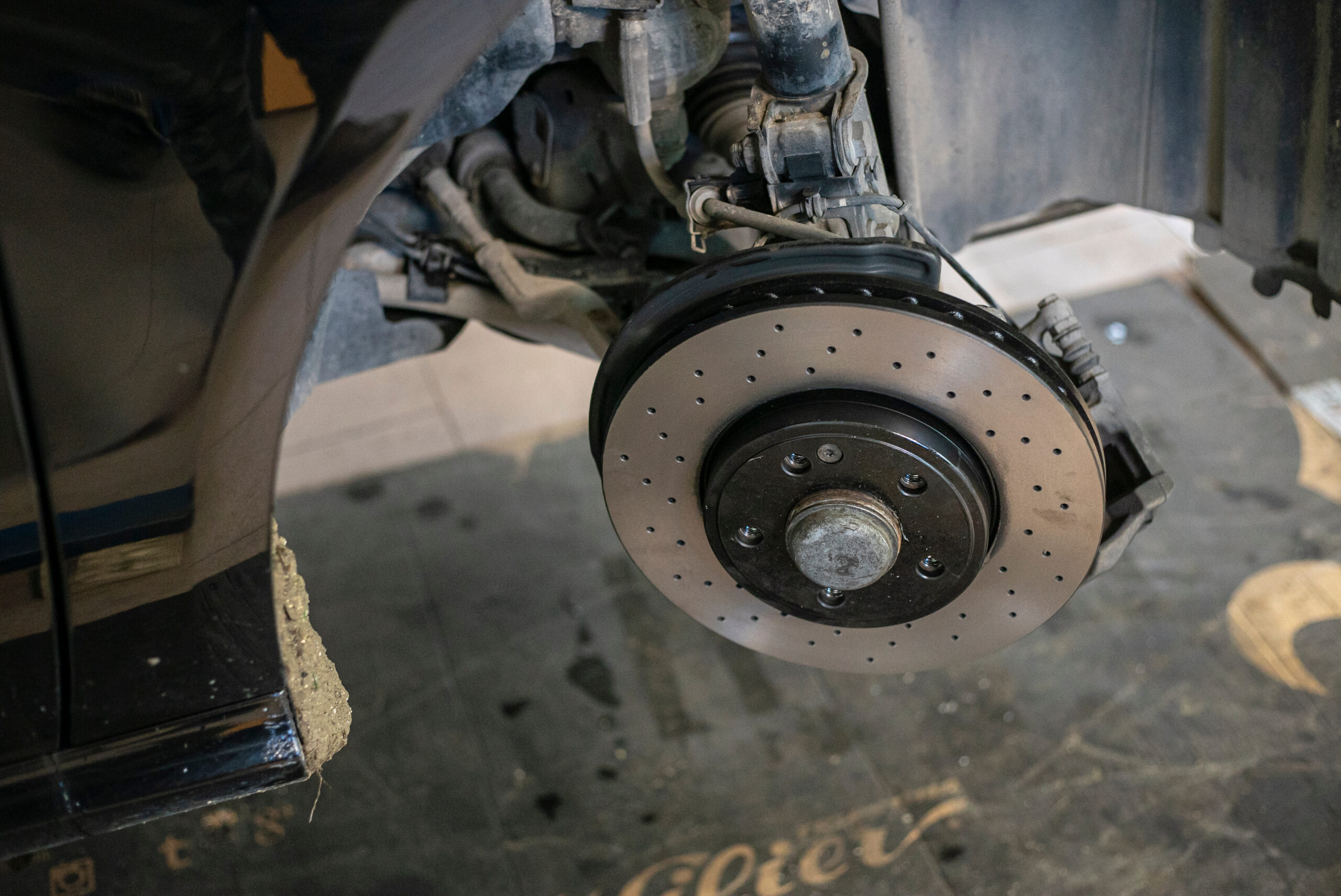 Mechanic replacing brake disc and caliper on car